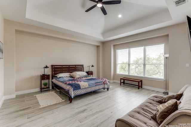 bedroom featuring a raised ceiling, light hardwood / wood-style flooring, and ceiling fan