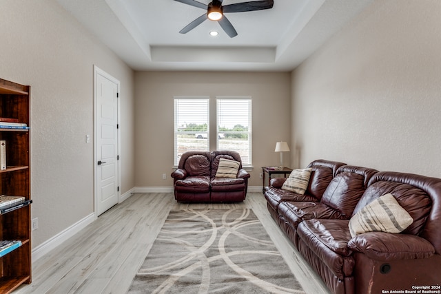 living room with a tray ceiling, light hardwood / wood-style flooring, and ceiling fan