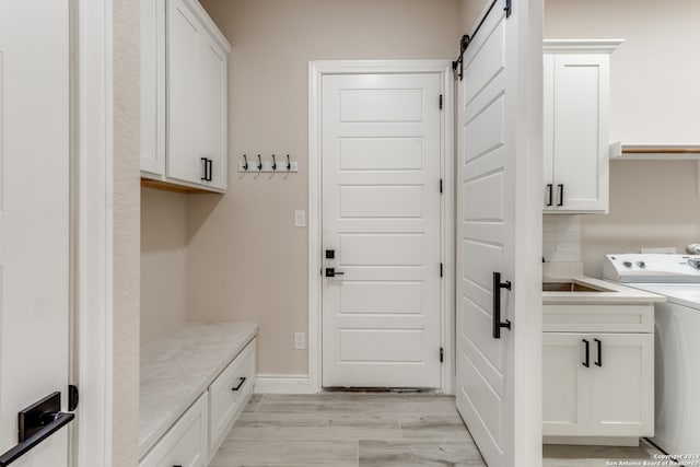 mudroom featuring a barn door, washer / dryer, and light wood-type flooring