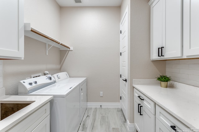 washroom with cabinets, separate washer and dryer, and light wood-type flooring