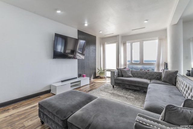 living room featuring visible vents, baseboards, wood finished floors, and recessed lighting