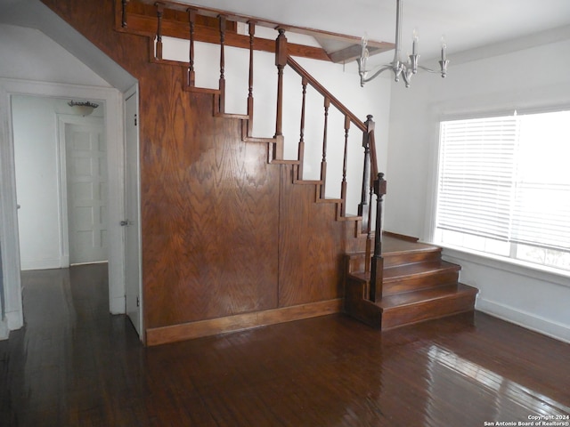 stairway with wood-type flooring and a notable chandelier