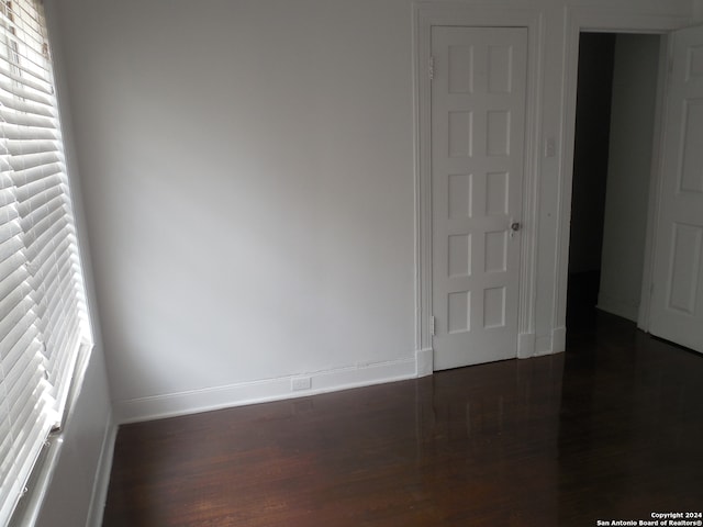 unfurnished bedroom with multiple windows, dark hardwood / wood-style flooring, and a closet