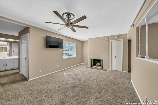 unfurnished living room featuring sink, ceiling fan, light colored carpet, and a fireplace