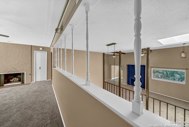 hallway featuring carpet, a textured ceiling, and a skylight