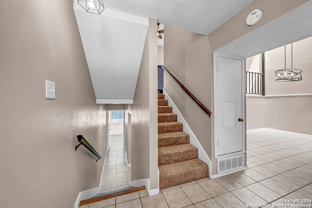 staircase featuring tile patterned flooring and a textured ceiling