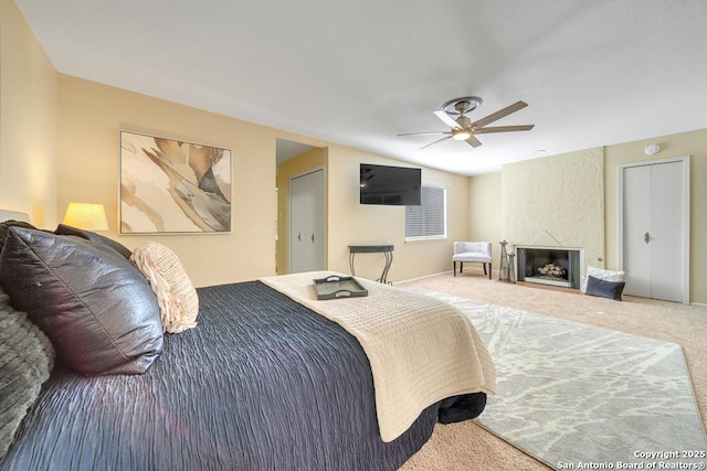 bedroom with carpet flooring, ceiling fan, and a fireplace