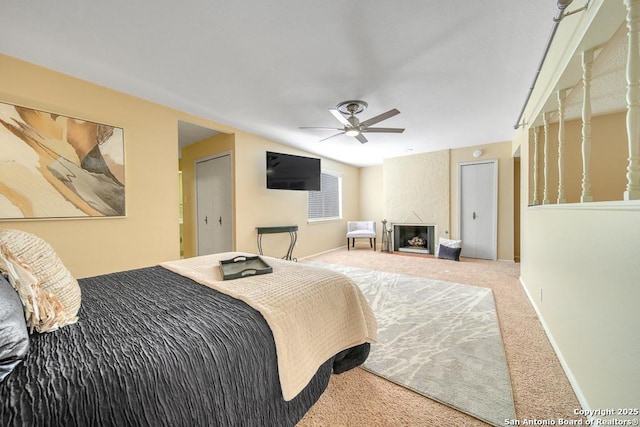 bedroom featuring ceiling fan, a large fireplace, and carpet floors