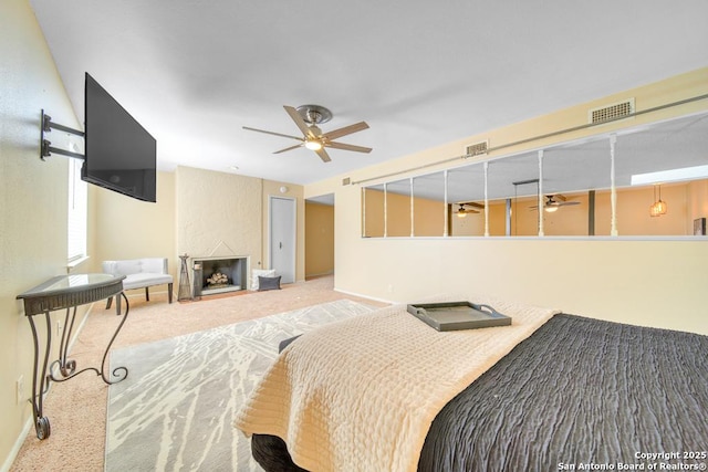 carpeted bedroom with ceiling fan and a large fireplace