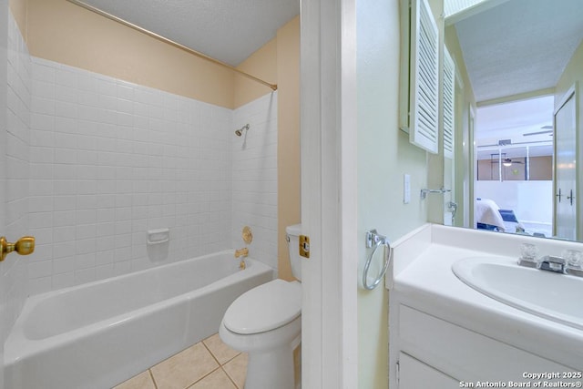 full bathroom featuring tile patterned flooring, a textured ceiling, toilet, vanity, and tiled shower / bath