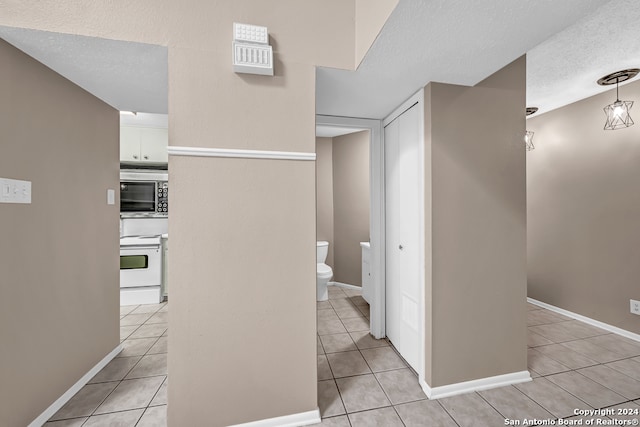 corridor with light tile patterned floors and a textured ceiling