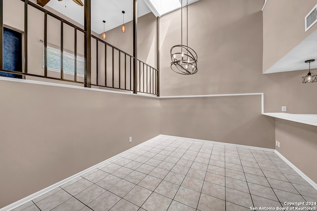 interior space featuring light tile patterned floors, ceiling fan with notable chandelier, and a high ceiling