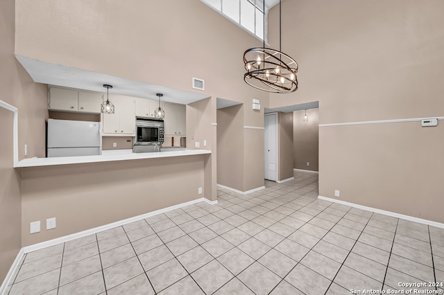 kitchen with kitchen peninsula, a towering ceiling, a notable chandelier, white fridge, and light tile patterned flooring