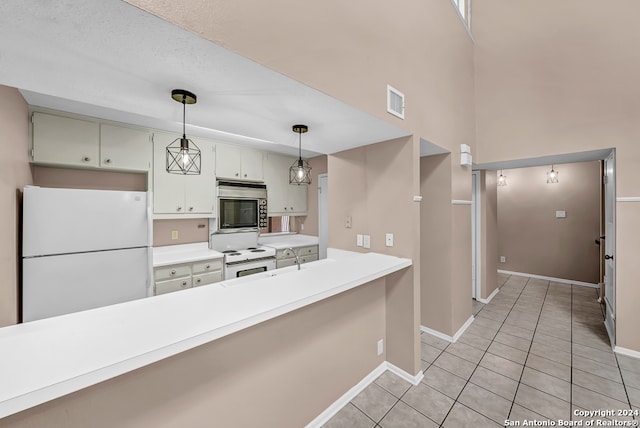 kitchen with light tile patterned floors, white appliances, and decorative light fixtures