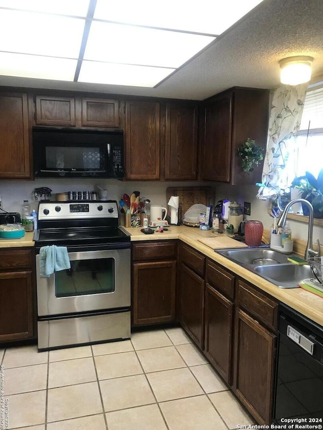 kitchen featuring a textured ceiling, black appliances, light tile patterned floors, sink, and dark brown cabinetry