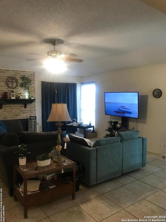 tiled living room with a textured ceiling, ceiling fan, and a fireplace