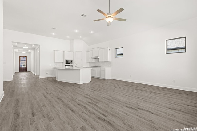 unfurnished living room featuring vaulted ceiling, ceiling fan, dark wood-type flooring, and sink