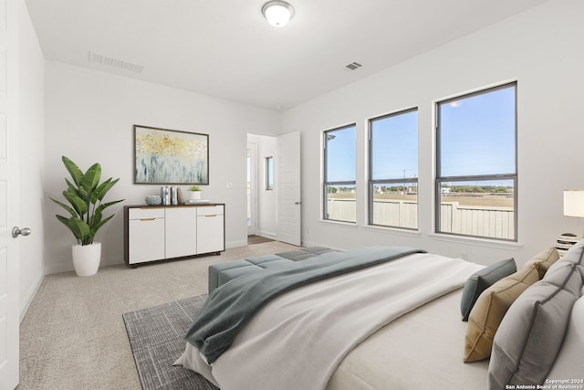 bedroom featuring baseboards, visible vents, and light colored carpet