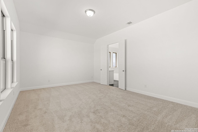 unfurnished bedroom with baseboards, visible vents, vaulted ceiling, and carpet flooring