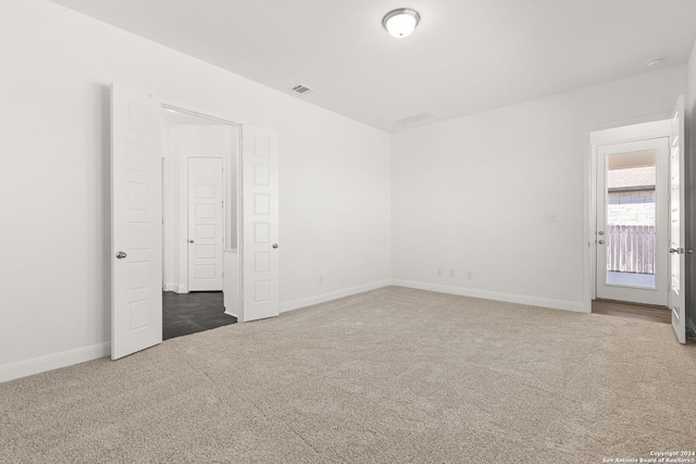 empty room featuring carpet floors, visible vents, and baseboards