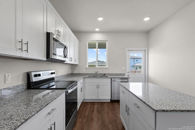 kitchen with appliances with stainless steel finishes, light stone countertops, white cabinets, and dark hardwood / wood-style floors