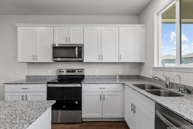 kitchen featuring dark hardwood / wood-style floors, light stone countertops, appliances with stainless steel finishes, sink, and white cabinetry