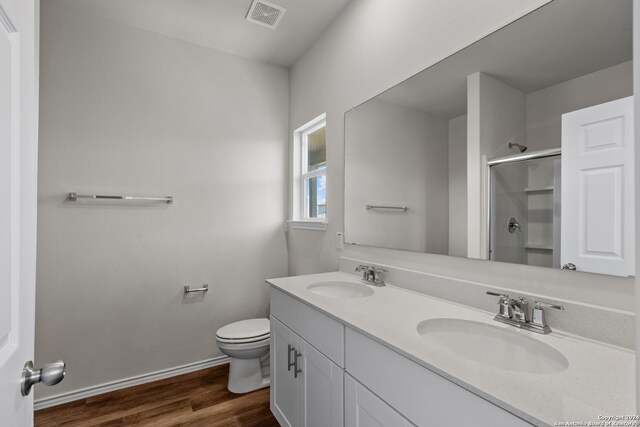 bathroom featuring vanity, toilet, hardwood / wood-style floors, and a shower with door