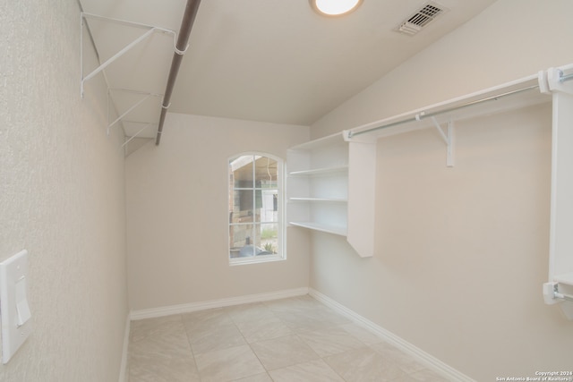 walk in closet with vaulted ceiling and light tile patterned flooring