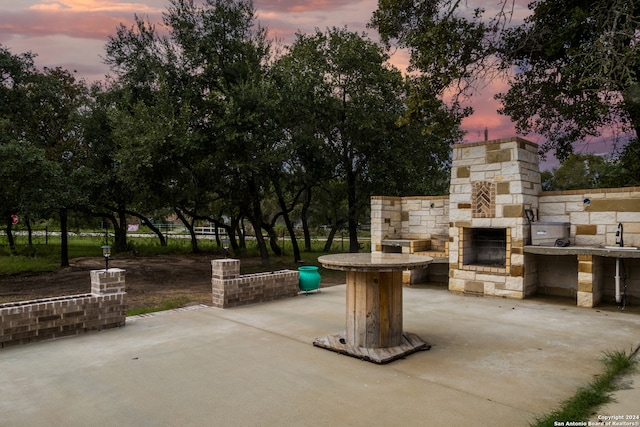 patio terrace at dusk with an outdoor stone fireplace