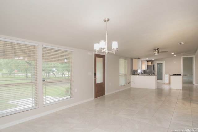 interior space featuring ceiling fan with notable chandelier, a wealth of natural light, and light tile patterned floors