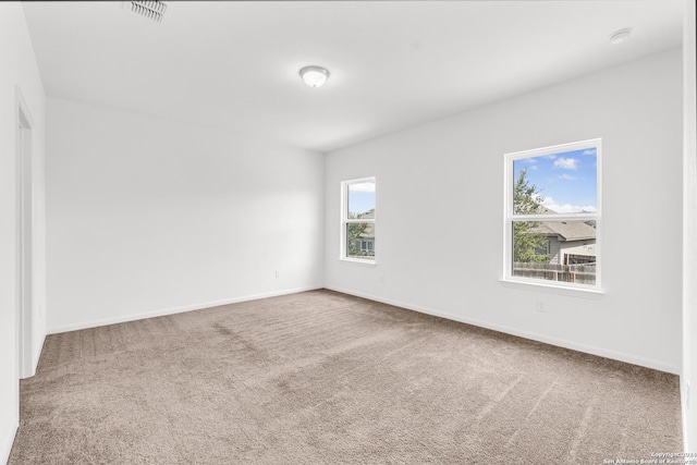 unfurnished room with carpet flooring, visible vents, and baseboards