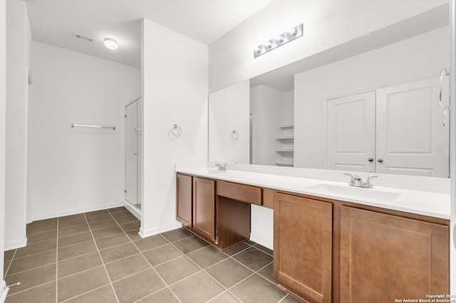 bathroom with a stall shower, tile patterned flooring, a sink, and double vanity