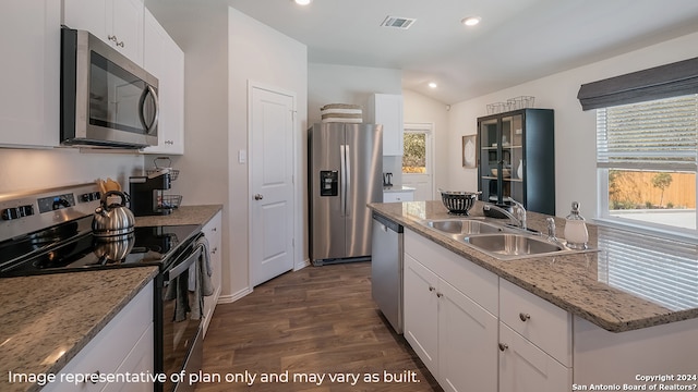 kitchen featuring dark wood-type flooring, appliances with stainless steel finishes, white cabinetry, and vaulted ceiling