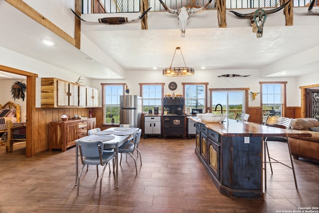 kitchen featuring dark hardwood / wood-style flooring, stainless steel refrigerator, an island with sink, a kitchen bar, and a textured ceiling