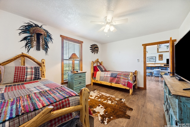 bedroom with a textured ceiling, ceiling fan, and dark hardwood / wood-style flooring