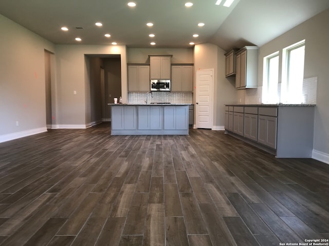 kitchen featuring stone countertops, dark hardwood / wood-style flooring, backsplash, and gray cabinetry