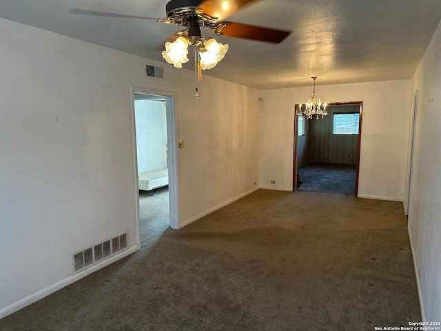 carpeted spare room featuring ceiling fan with notable chandelier