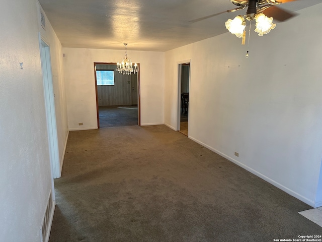 carpeted empty room featuring ceiling fan with notable chandelier