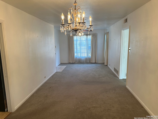 carpeted empty room with a notable chandelier