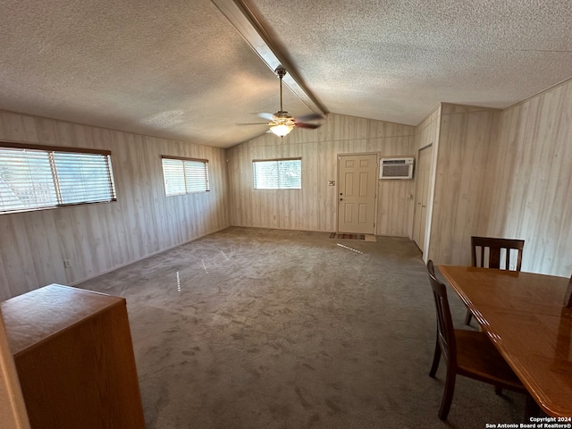 interior space with a textured ceiling, ceiling fan, carpet floors, and vaulted ceiling with beams