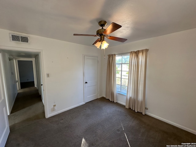 unfurnished bedroom featuring ceiling fan, dark colored carpet, and a closet