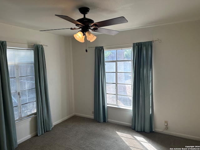 carpeted spare room featuring a healthy amount of sunlight and ceiling fan