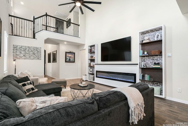 living room with a glass covered fireplace, wood finished floors, a high ceiling, baseboards, and ceiling fan