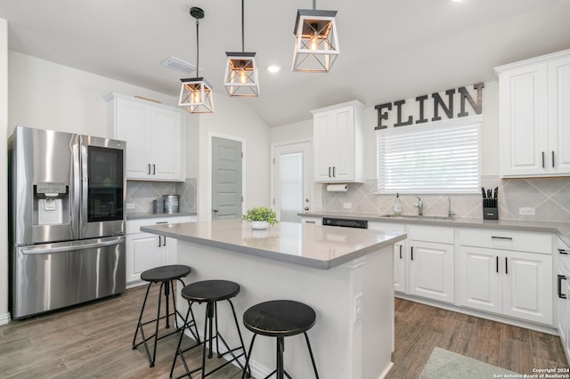 kitchen with a center island, white cabinetry, stainless steel fridge, pendant lighting, and decorative backsplash