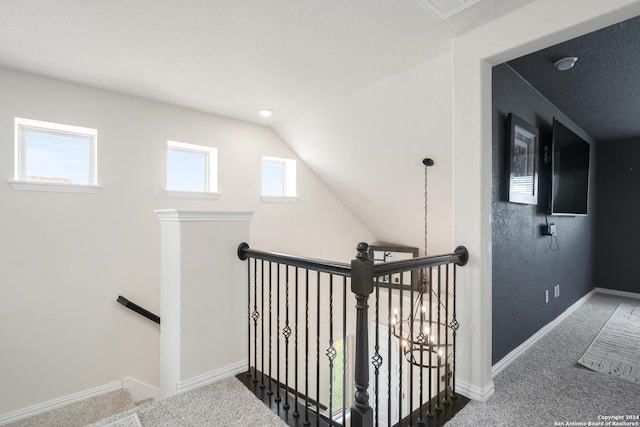 corridor with baseboards, an upstairs landing, lofted ceiling, and carpet floors