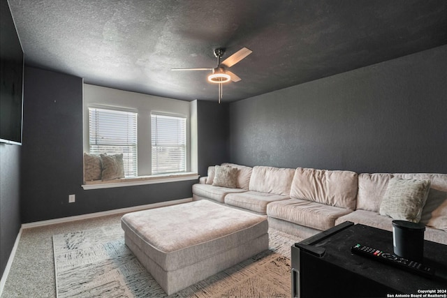 carpeted living area featuring a textured ceiling, a textured wall, baseboards, and ceiling fan