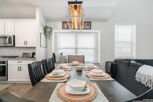 dining area featuring light wood finished floors, a toaster, an inviting chandelier, and lofted ceiling