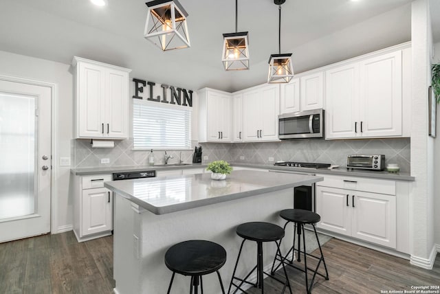 kitchen with a breakfast bar, stainless steel microwave, white cabinetry, and dark wood-style floors