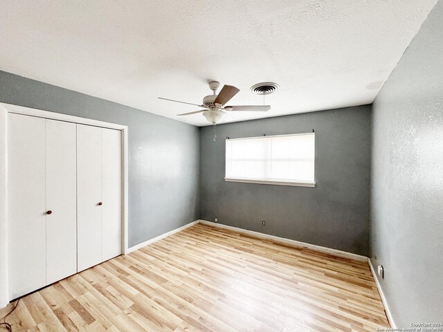 unfurnished bedroom with a closet, a textured ceiling, ceiling fan, and light hardwood / wood-style floors