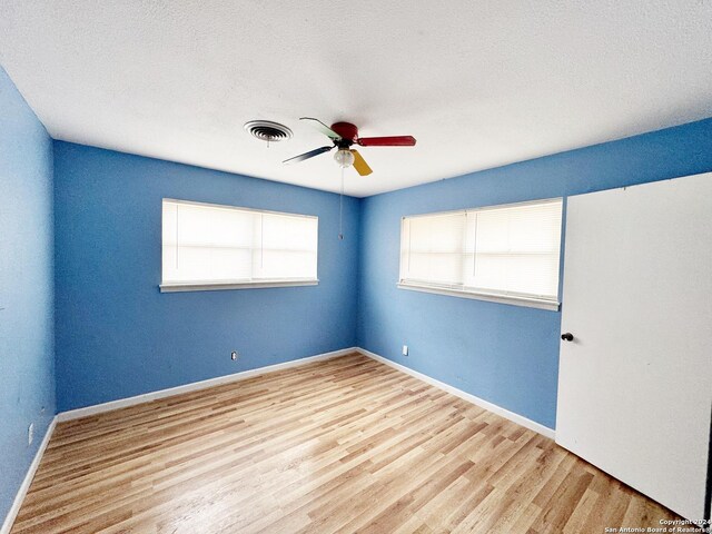 empty room with a textured ceiling, hardwood / wood-style floors, and ceiling fan